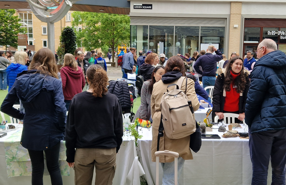 Image of four visitors and one researcher at the Flourishing & Wellbeing stand during BRC's Open Day 2024